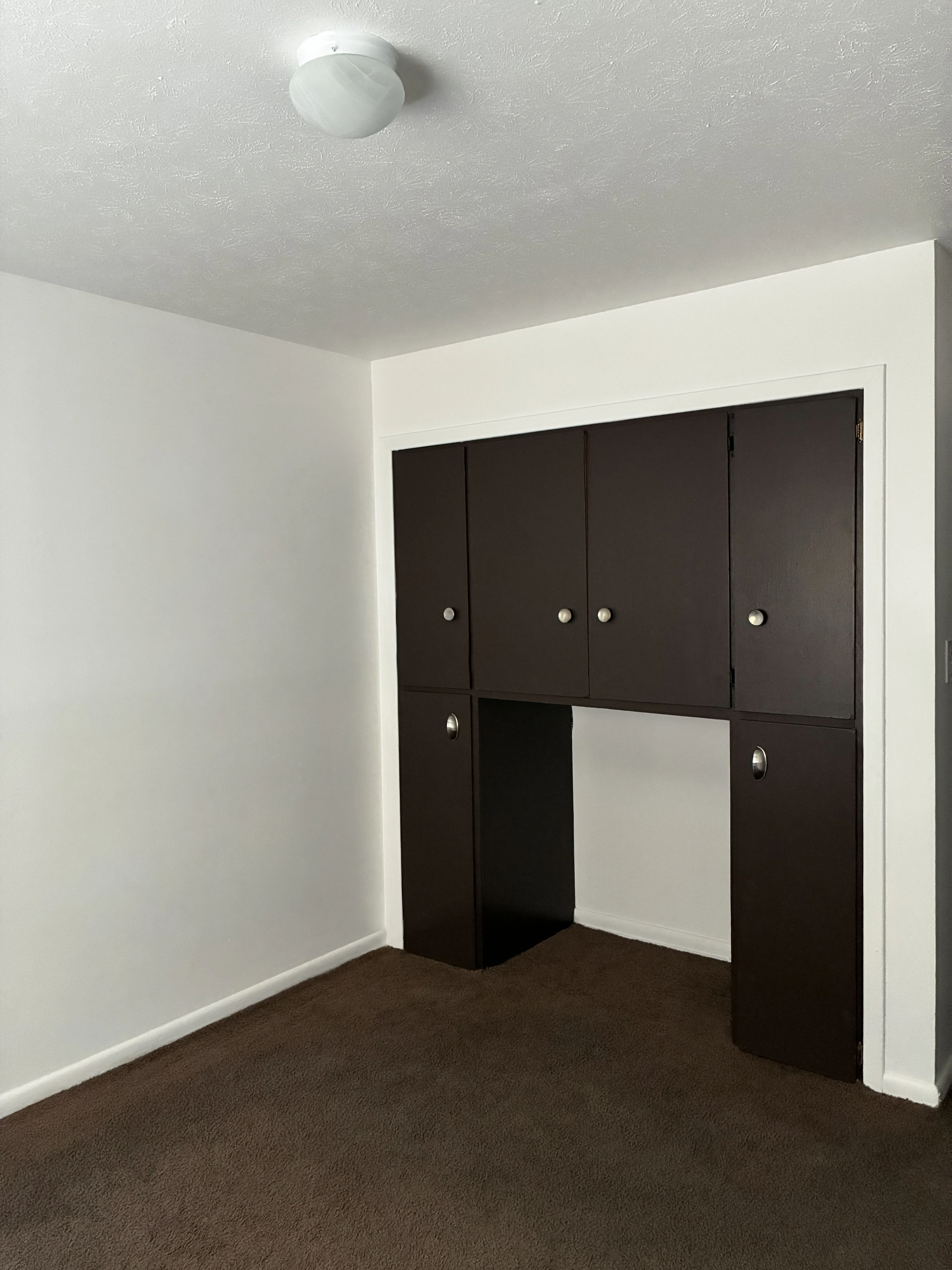 Bedroom with built-in dark wood cabinets and desk area